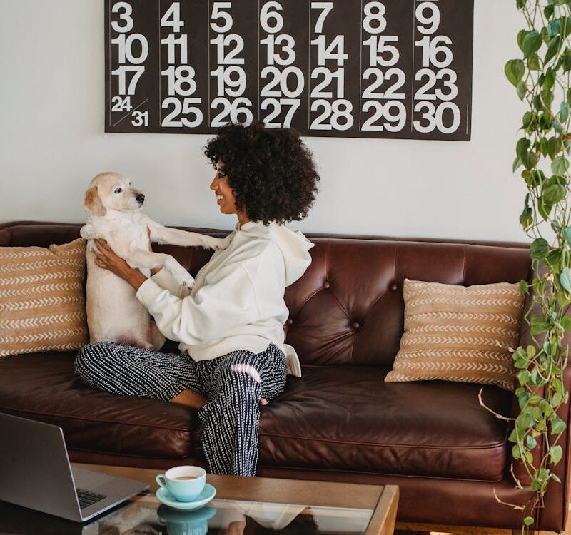woman with her dog on a brown couch with tan pillows